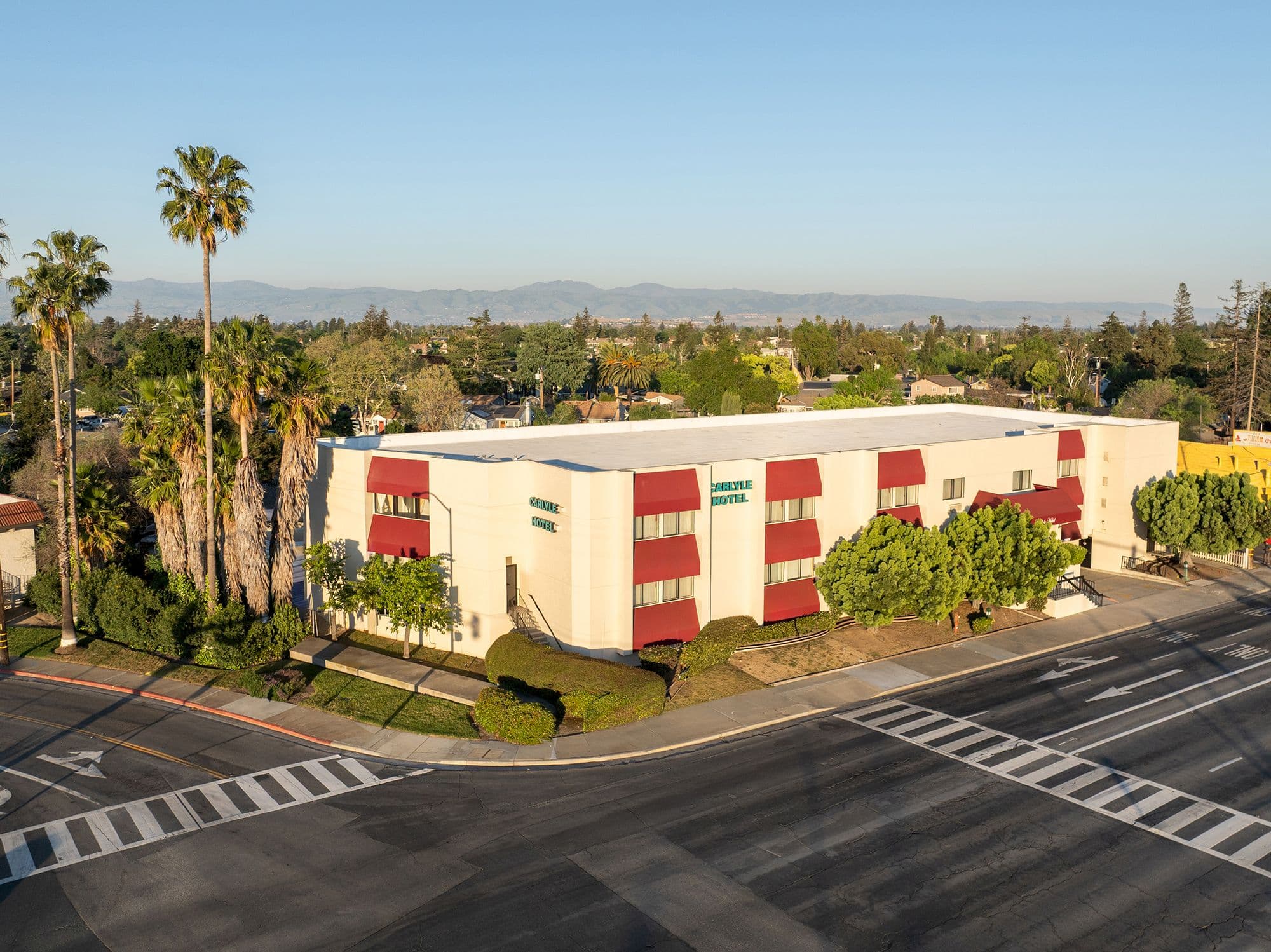 Aerial view of the Carlyle Hotel in Campbell, with its red awnings, tall palms and the hills beyond