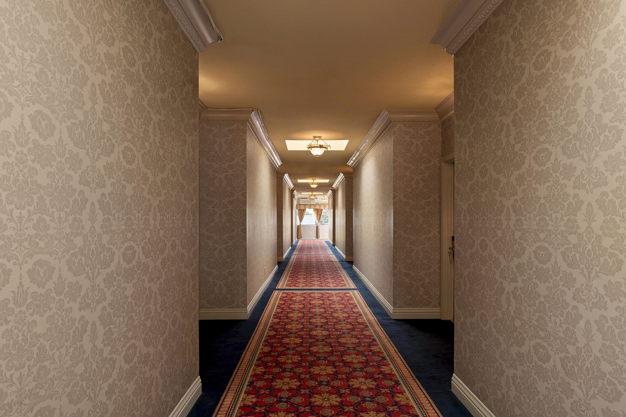 Guest corridor with damask walls and a red patterned runner