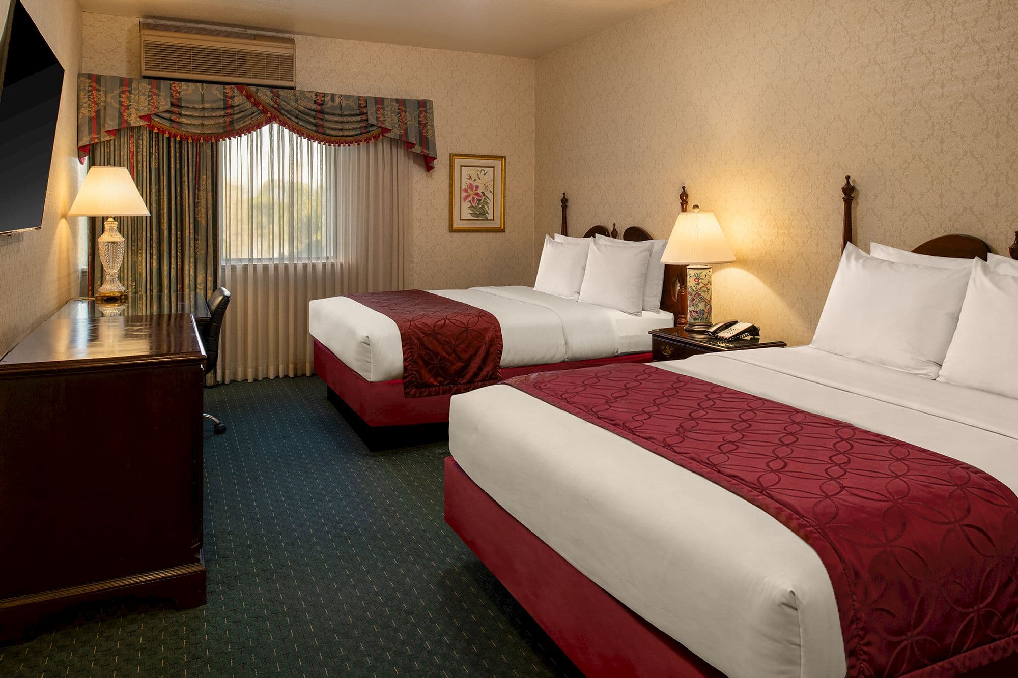 Guest room with two queen beds, burgundy runners and cherry wood headboards