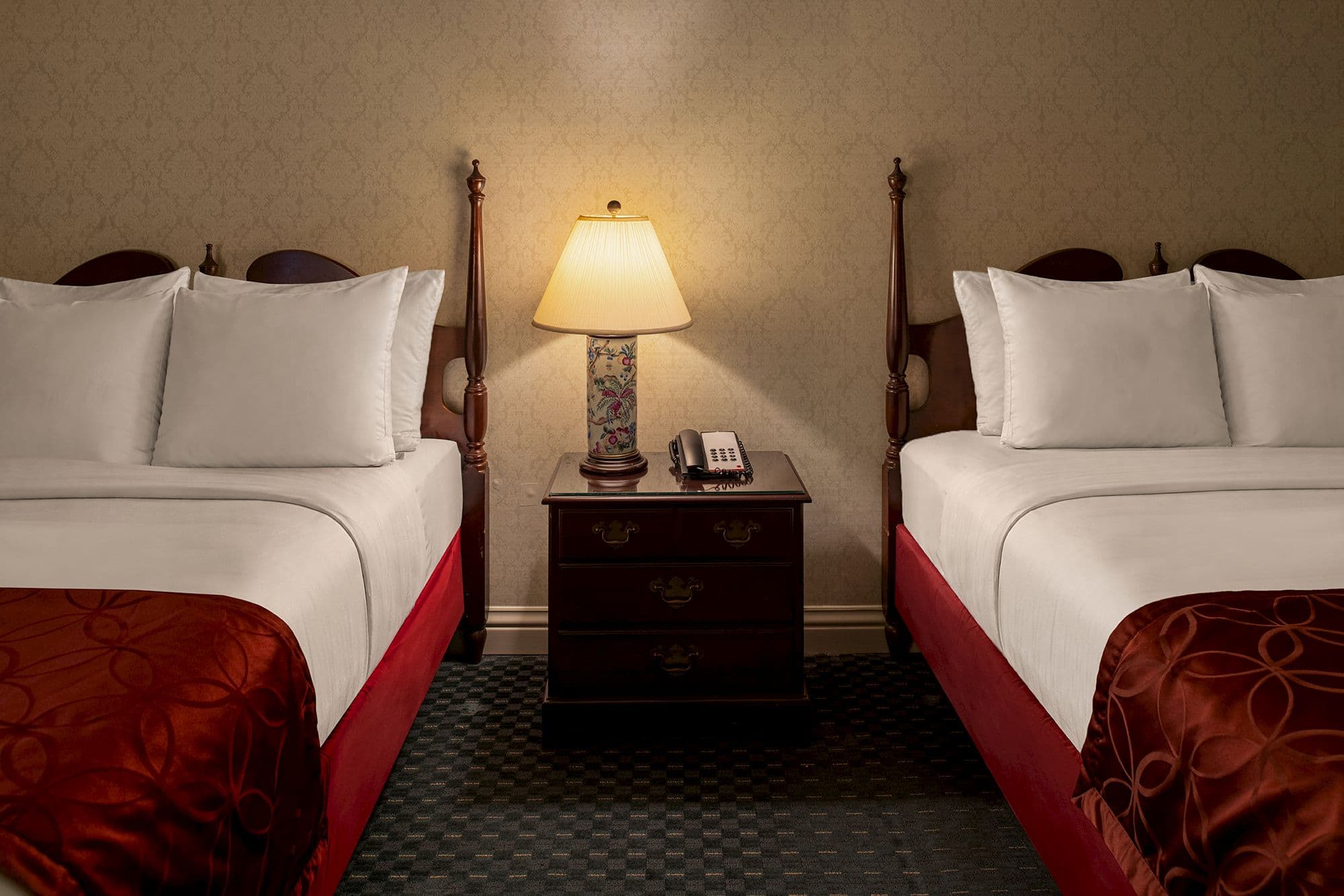 Porcelain lamp and telephone on a nightstand between two queen beds