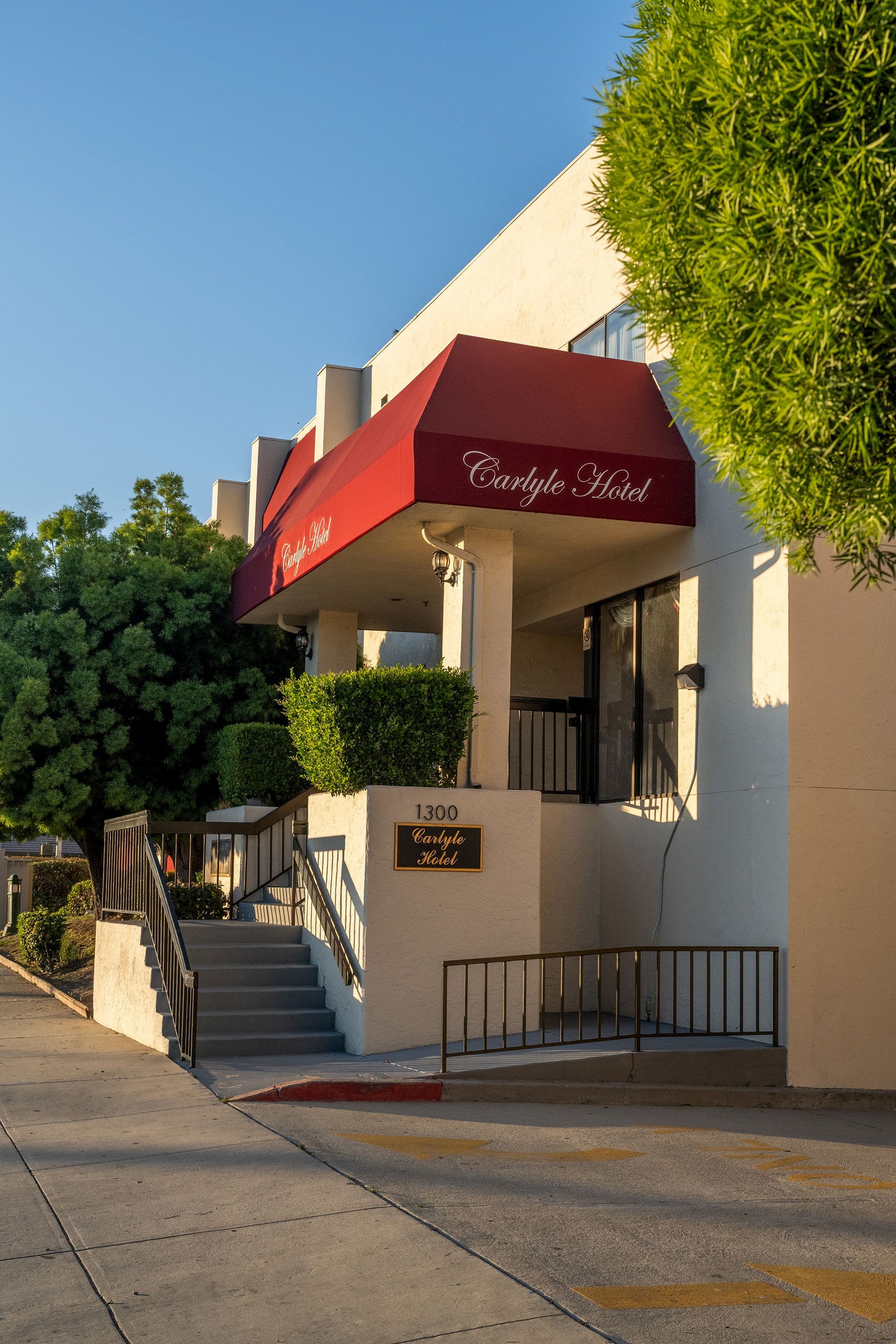 The Carlyle Hotel entrance under a red awning, with steps and a ramp up from the sidewalk