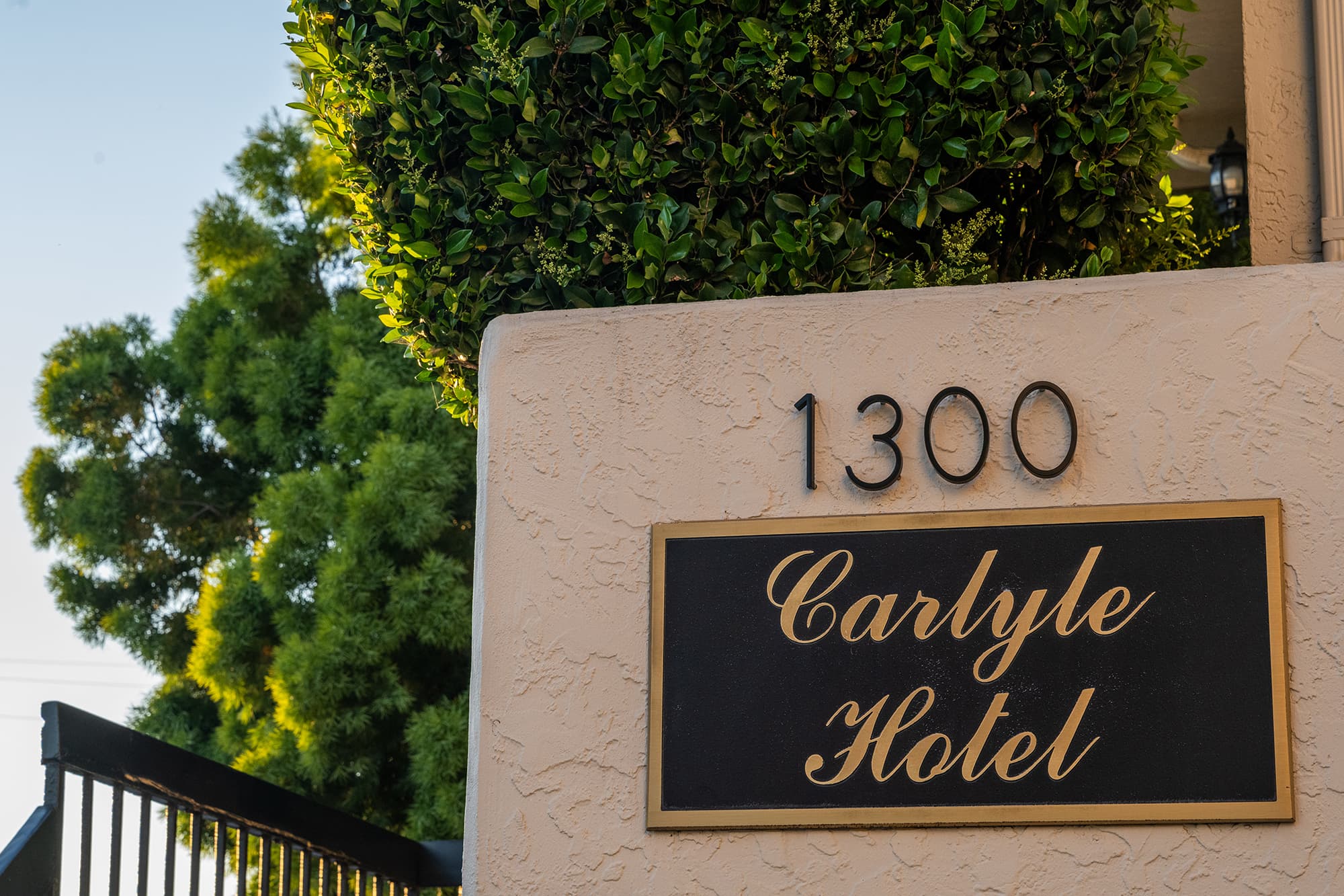 Black and gold Carlyle Hotel plaque beneath the 1300 street number on a stucco wall
