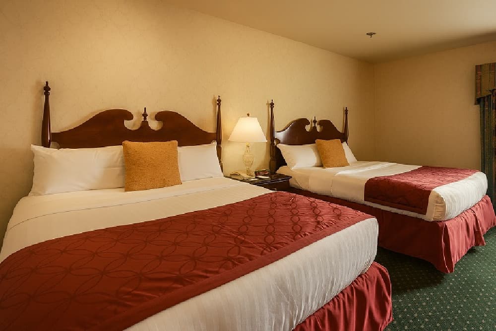 Two queen beds with carved cherry wood headboards and a crystal lamp on the nightstand